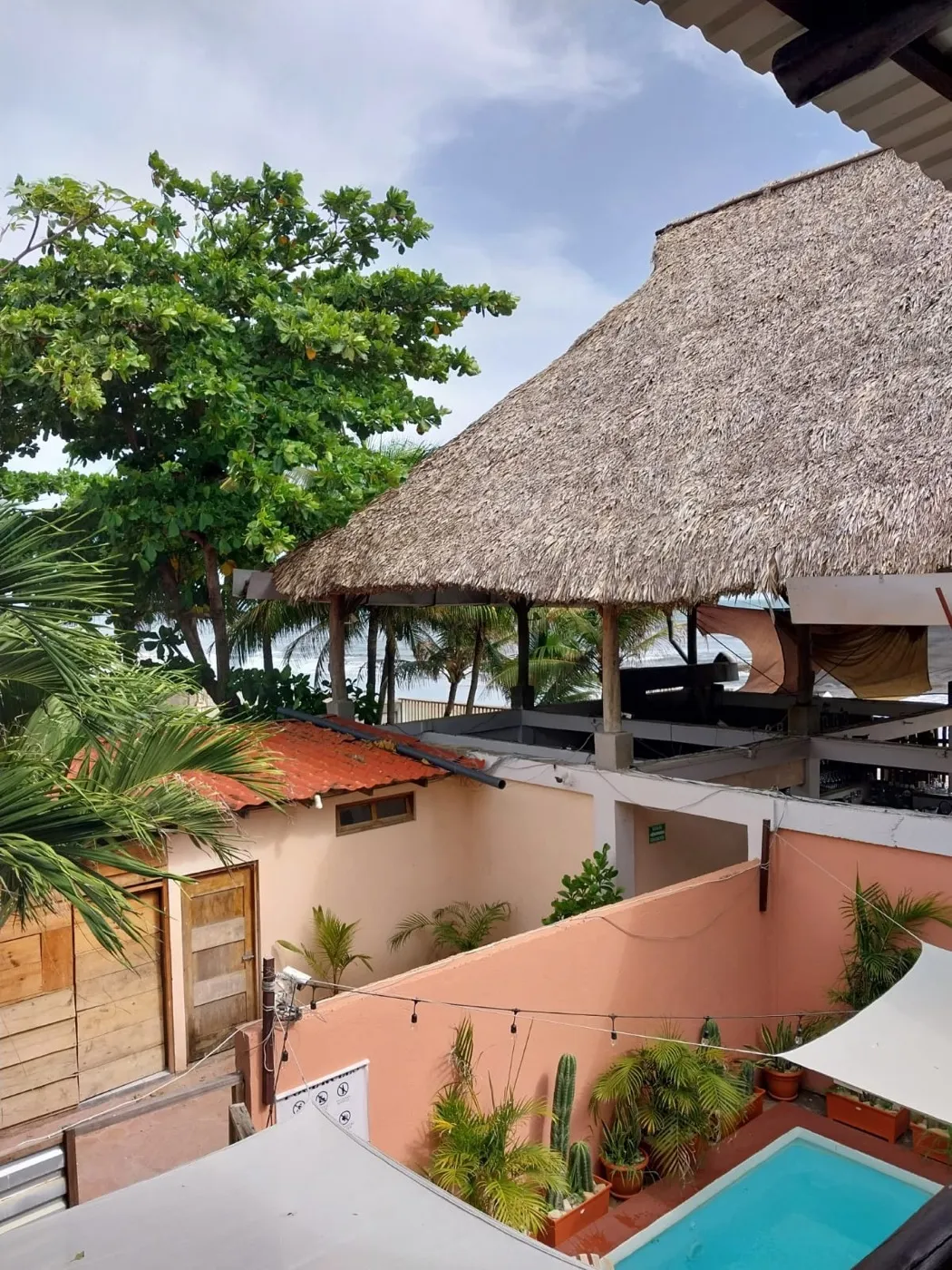 El Escondite seen from above — the thatched terrace, private pool and palms with the Pacific beyond